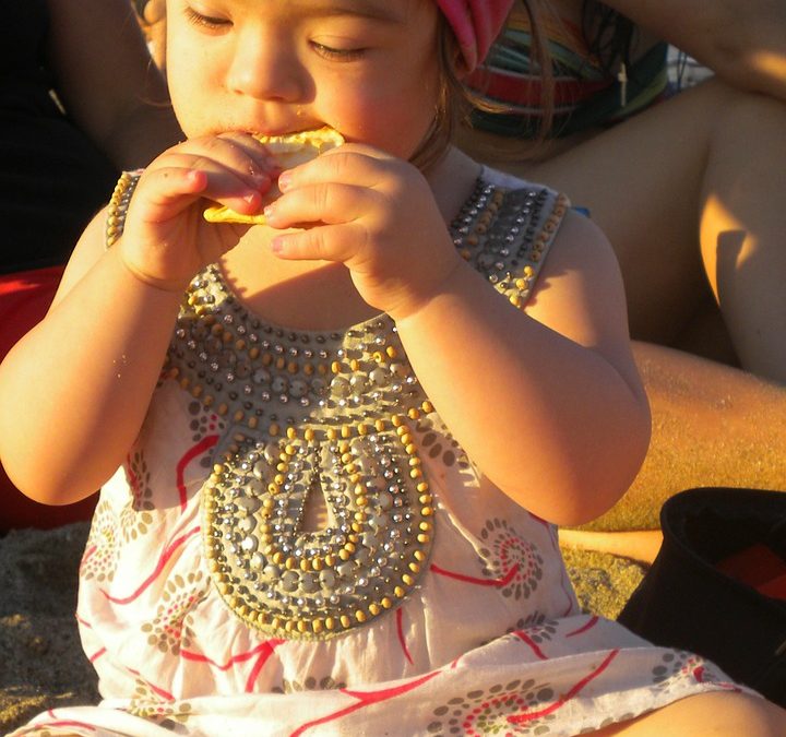 bebé con Síndrome de Down comiendo una galleta